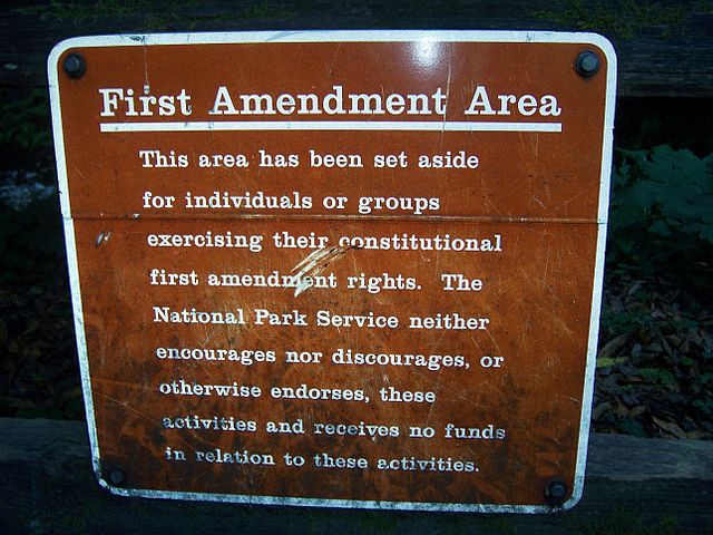 Picture of a sign from Muir Woods reading: 'First Amendment
     Area: This area has been set aside for individuals or groups
     exercising their constitutional first amendment rights. The
     National Park Service neither encourages nor discourages, or
     otherwise endorses, these activities and receives no funds in
     relation to these activities.'