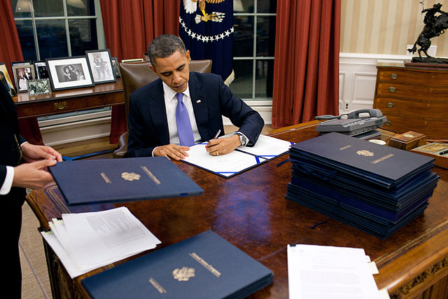 President Obama signing legislation in the Oval Office.